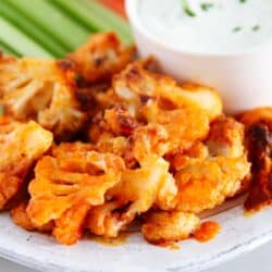 Baked buffalo cauliflower wings on a plate with ranch dressing.