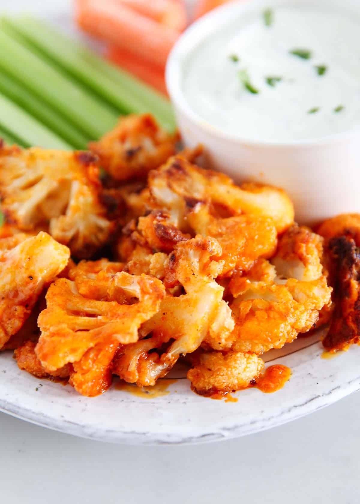 Baked buffalo cauliflower wings on a plate with ranch dressing.