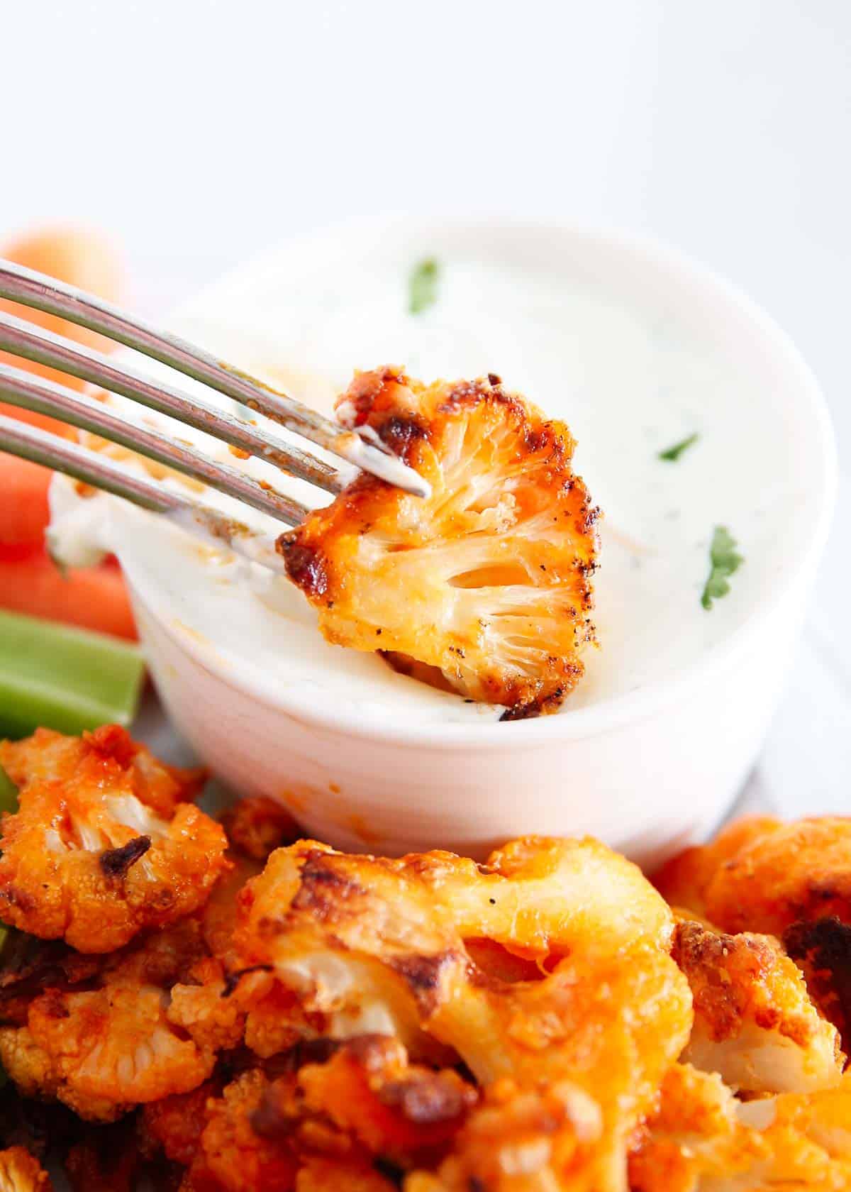 Dipping a buffalo cauliflower wing into dressing.