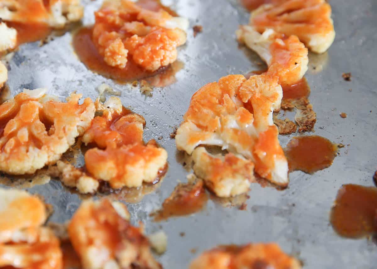 Tossing cauliflower bites with buffalo sauce.