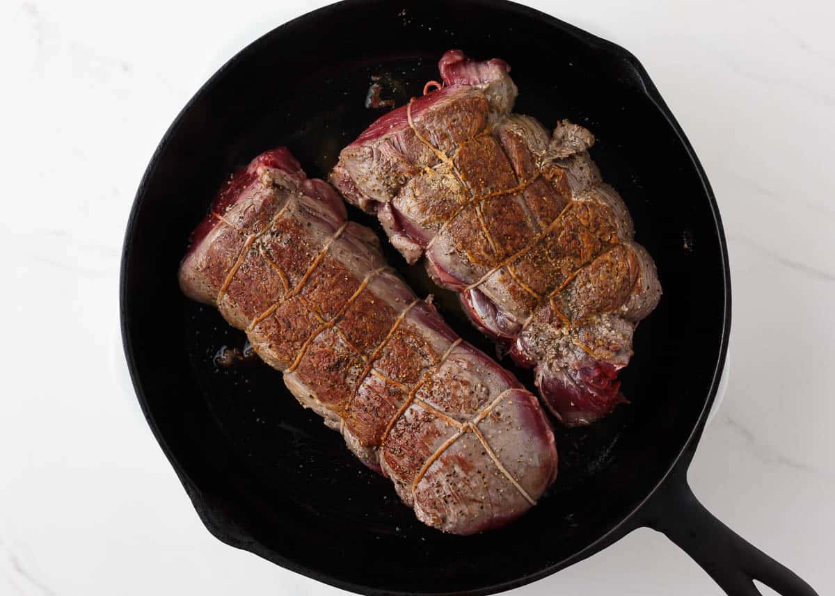 Beef tenderloin searing in a hot pan.