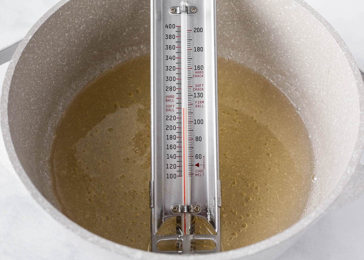 Water, sugar and corn syrup with a candy thermometer in a pot.