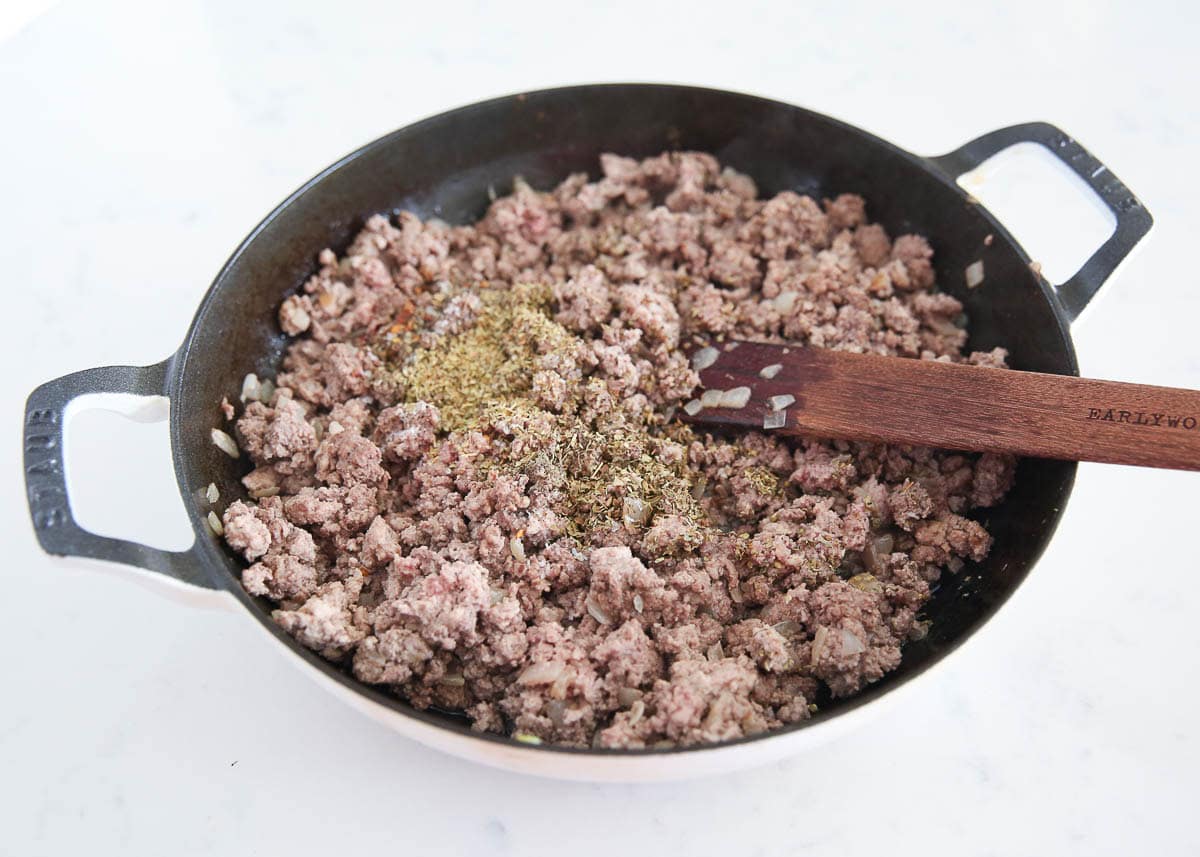 Meat with seasonings in a skillet.