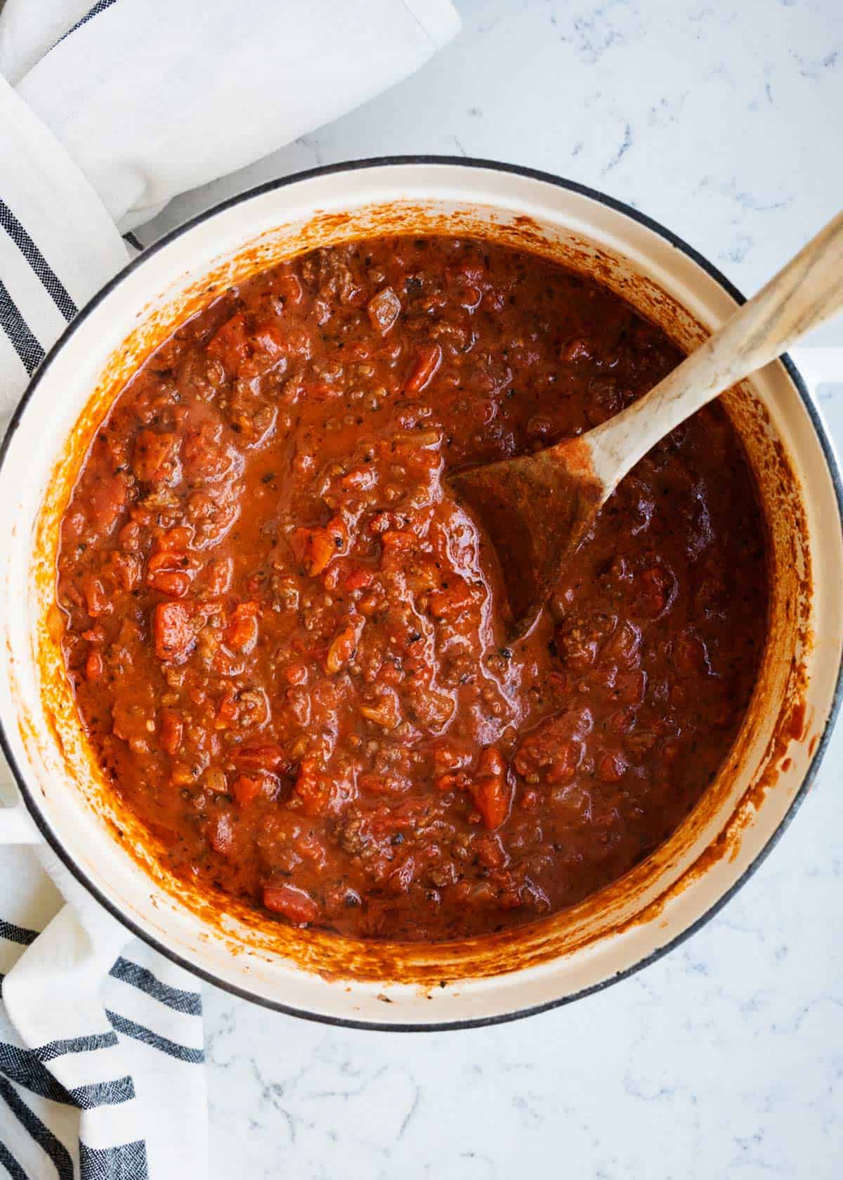 Spaghetti bolognese sauce in a pot with wooden spoon.