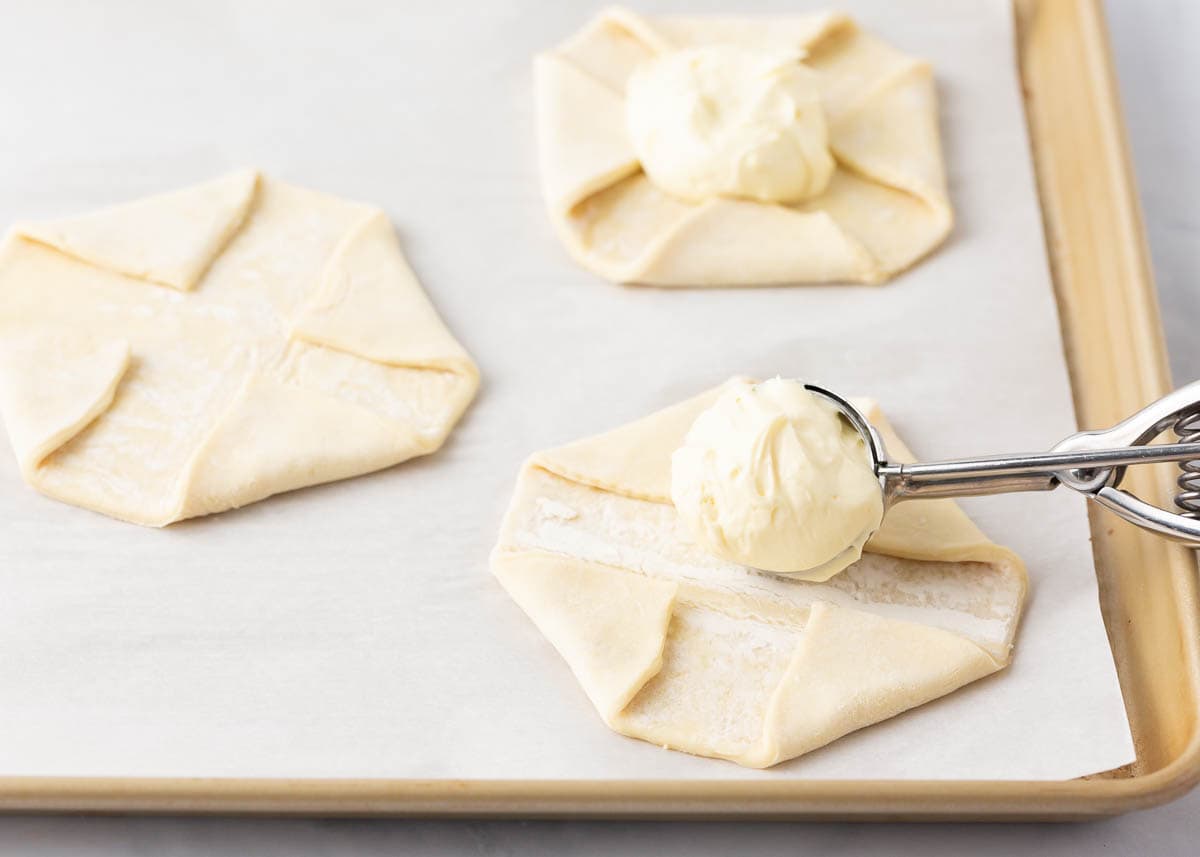 Scooping filling into the center of unbaked danish.