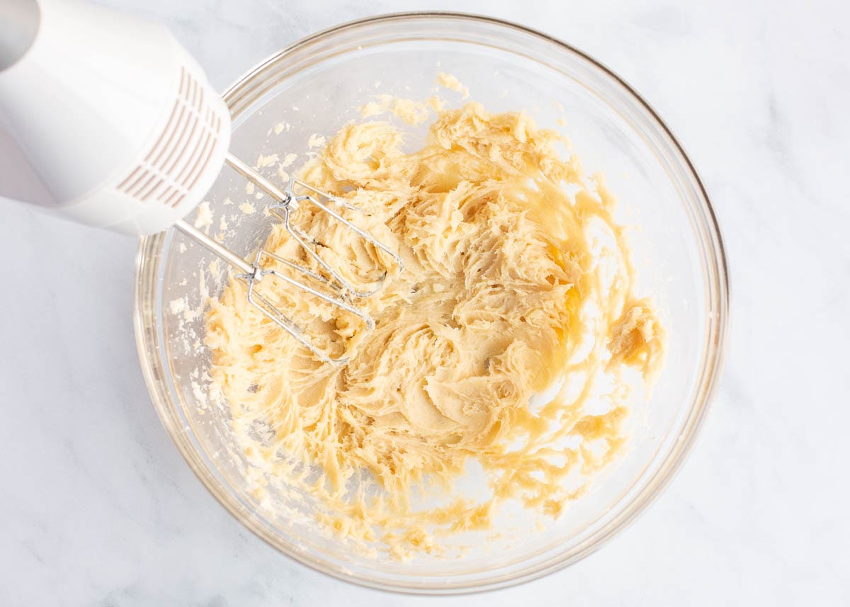 Creaming butter and sugar in a bowl with a hand mixer.