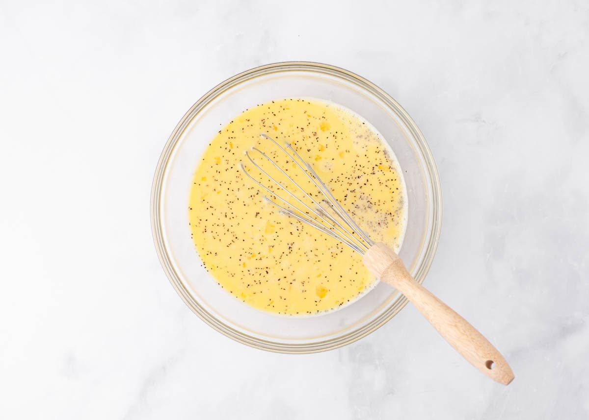 Whisking an egg mixture in a glass bowl.