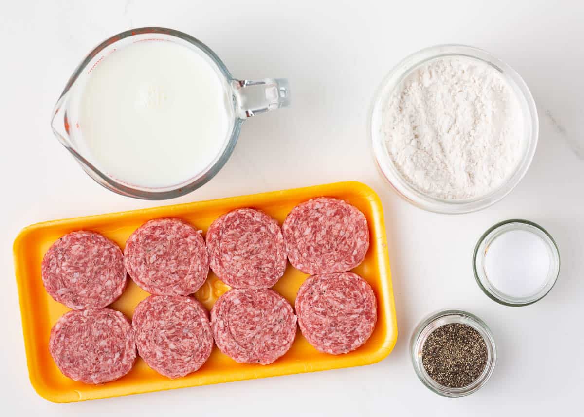 Sausage, milk, flour, salt and pepper on the counter.