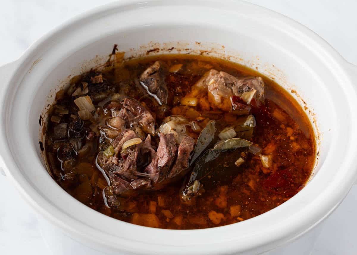 Cooked beef barbacoa in a white crockpot.