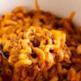 Cheeseburger casserole recipe in a white pot with serving spoon.