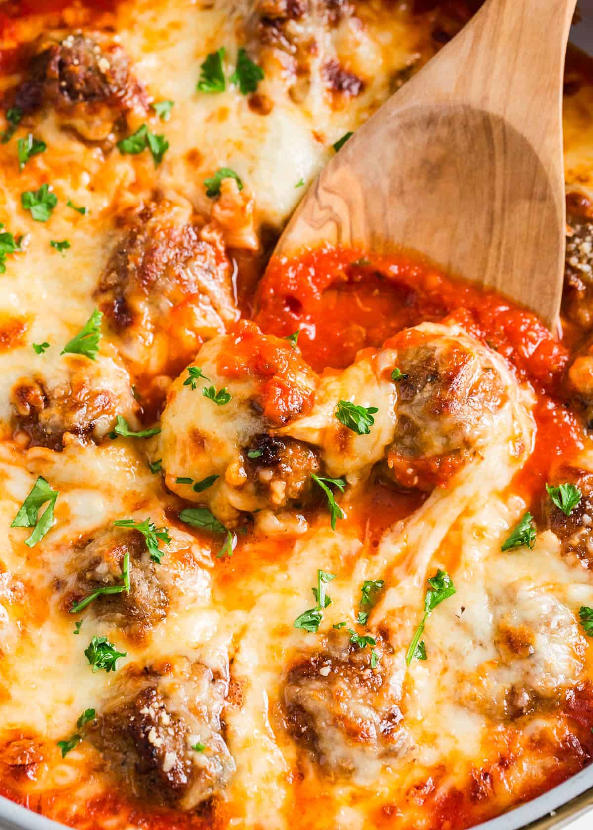 Chicken parmesan meatballs in skillet with serving spoon.