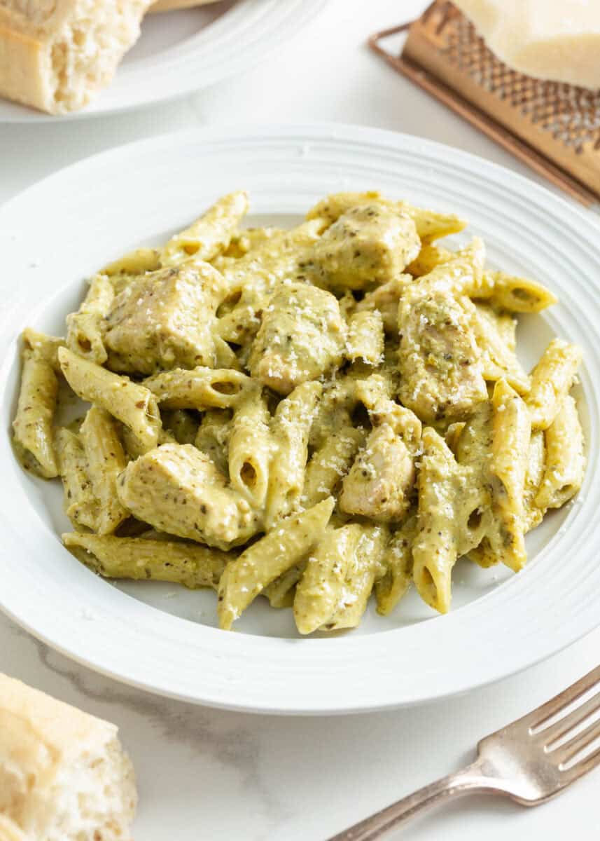 Chicken pesto pasta on a white plate. 