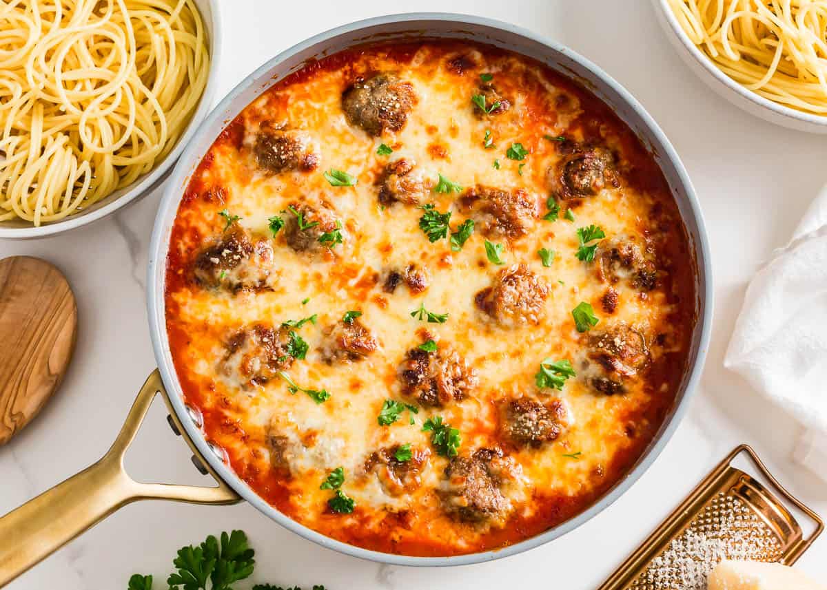 Cooked chicken parmesan meatballs in a skillet. 