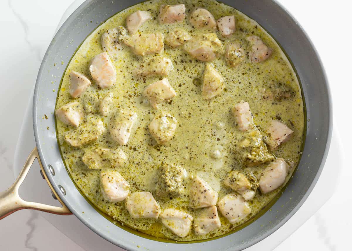 Chicken with pesto and cream in a skillet.