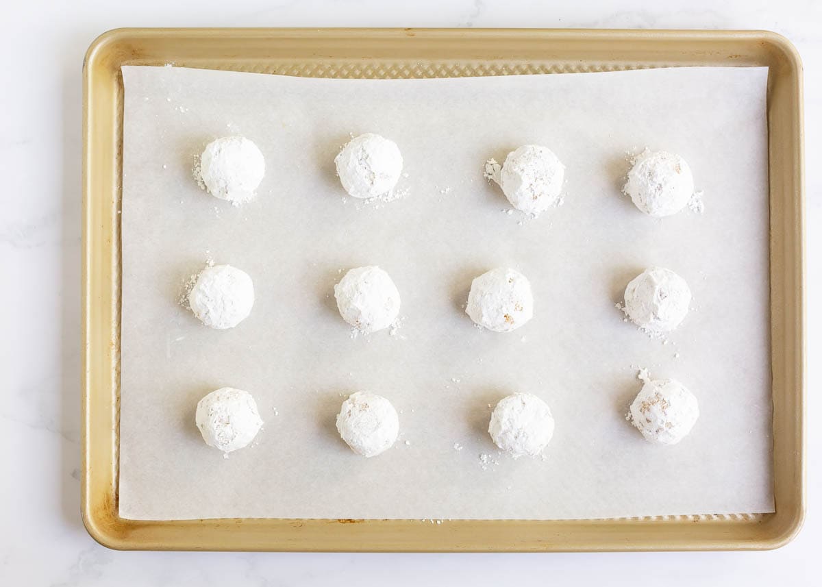 Lemon crinkle cookies covered in powdered sugar on baking sheet.