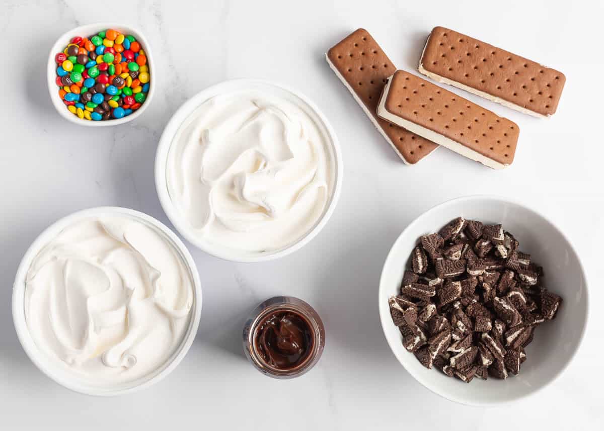 Whip cream, ice cream sandwiches, Oreos, hot fudge and M&Ms on the counter.