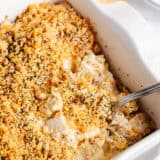 Poppy seed chicken casserole with serving spoon in white dish.