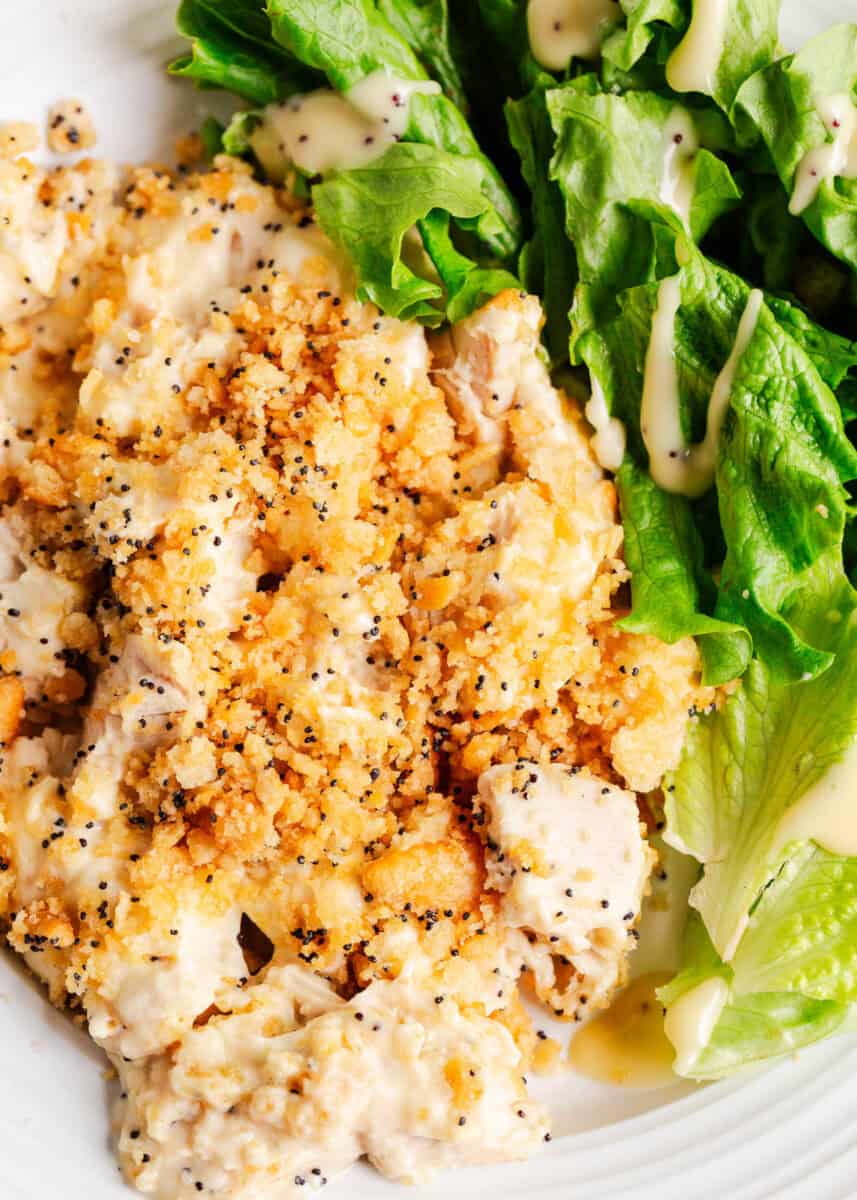 Poppy seed chicken casserole on a plate with salad.