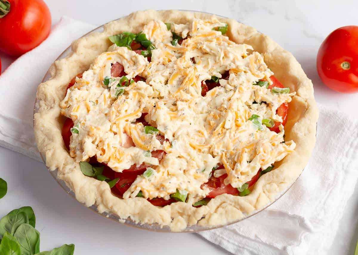 A cheese mixture on top of tomatoes in a pie crust.