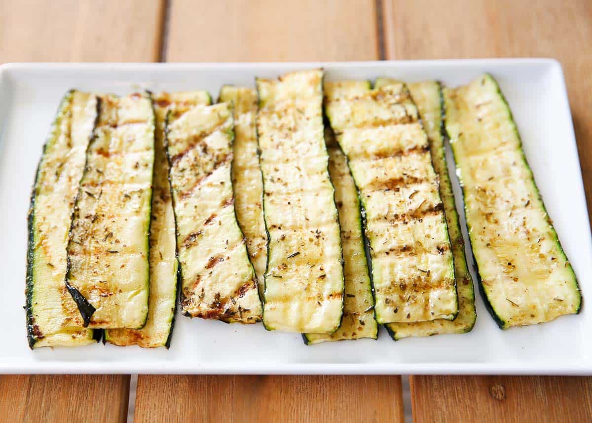 Grilled zucchini sliced on a white plate.