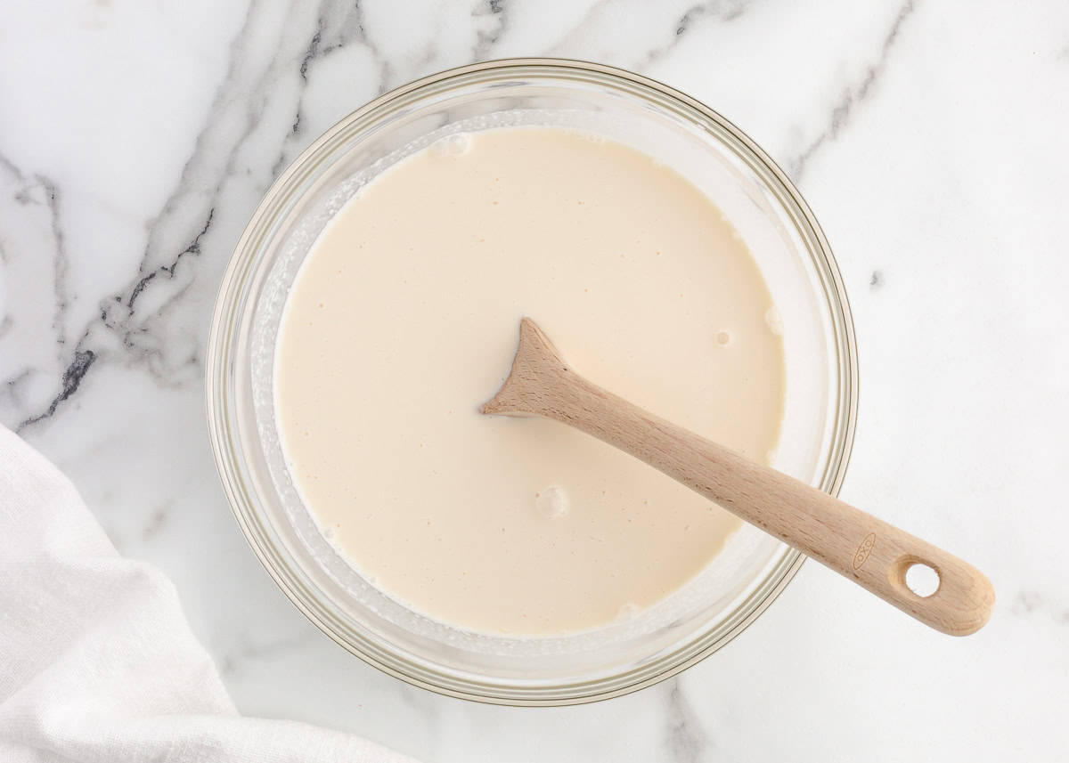 Heavy cream, sugar, milk and vanilla being stirred in a bowl.