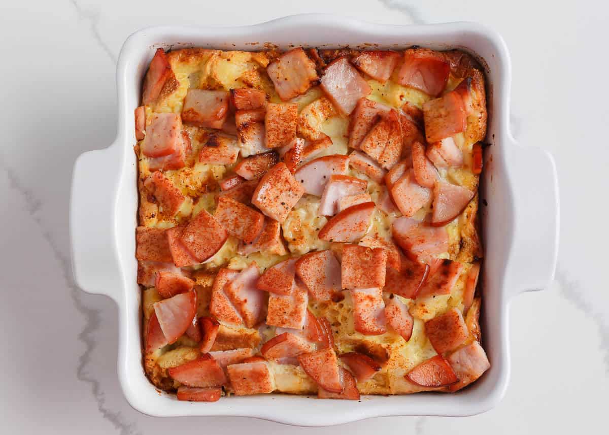 Baked eggs benedict casserole in a white baking dish.