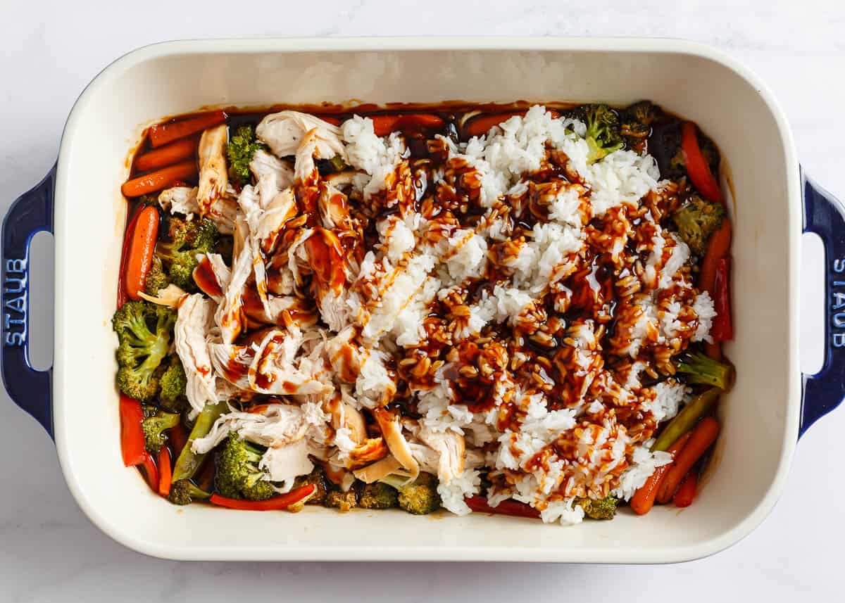 Shredded chicken with vegetables and teriyaki sauce in a white baking dish.