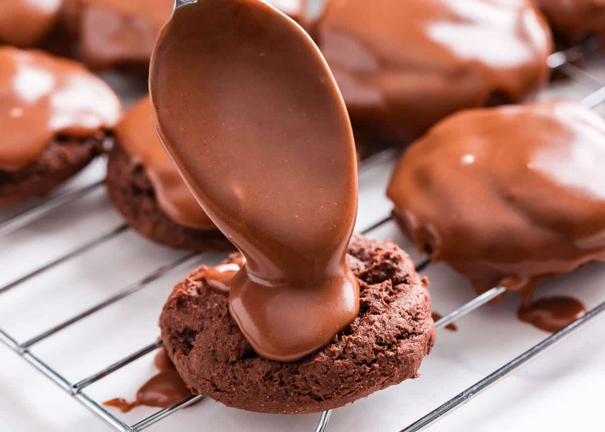 Pouring chocolate glaze over cookies.