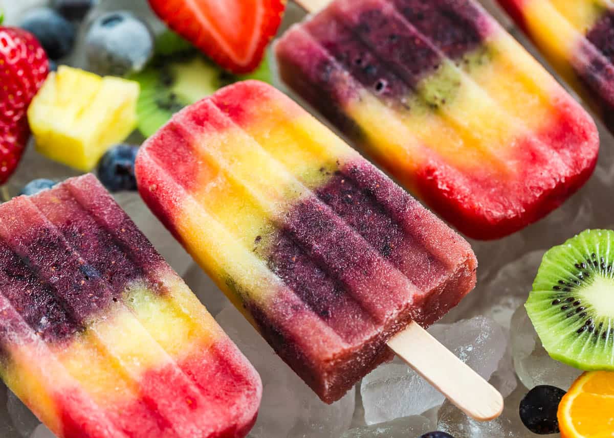 Three rainbow popsicles on ice.