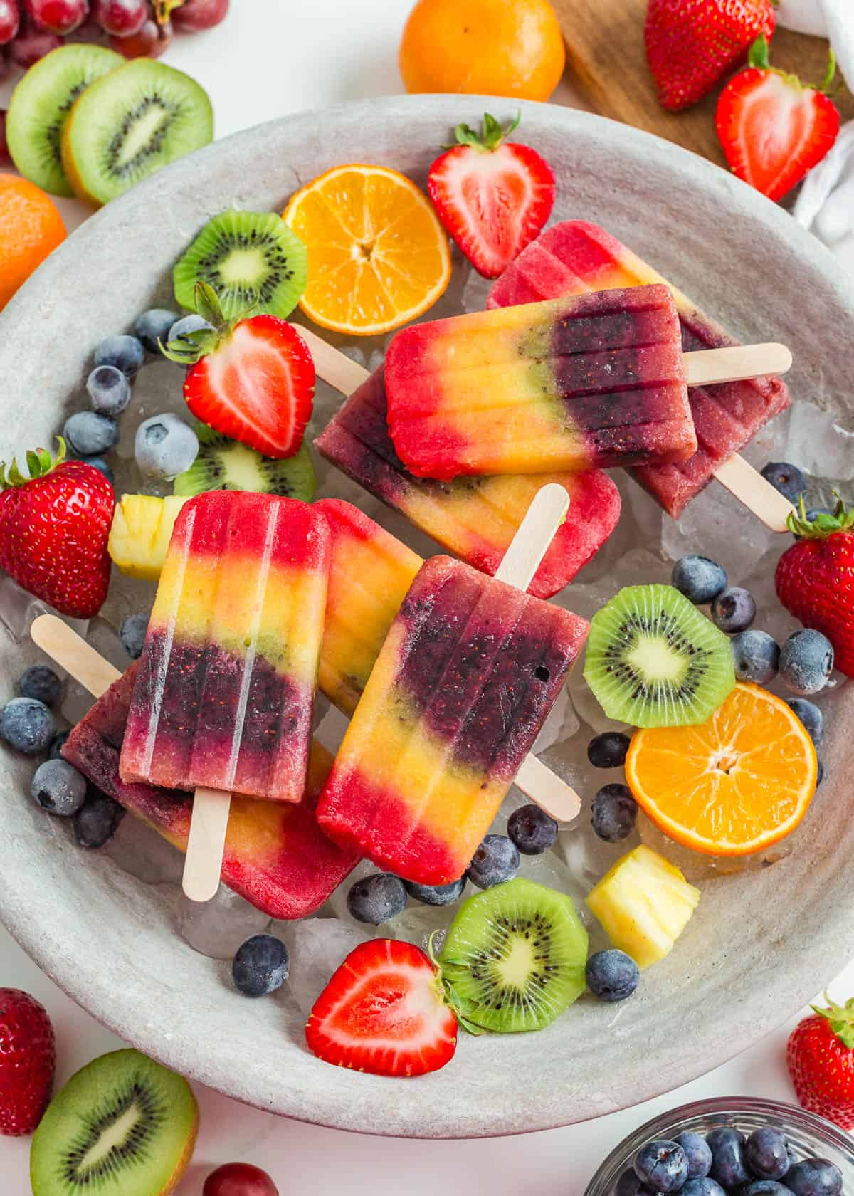 A tray with rainbow popsicles and fresh fruit.