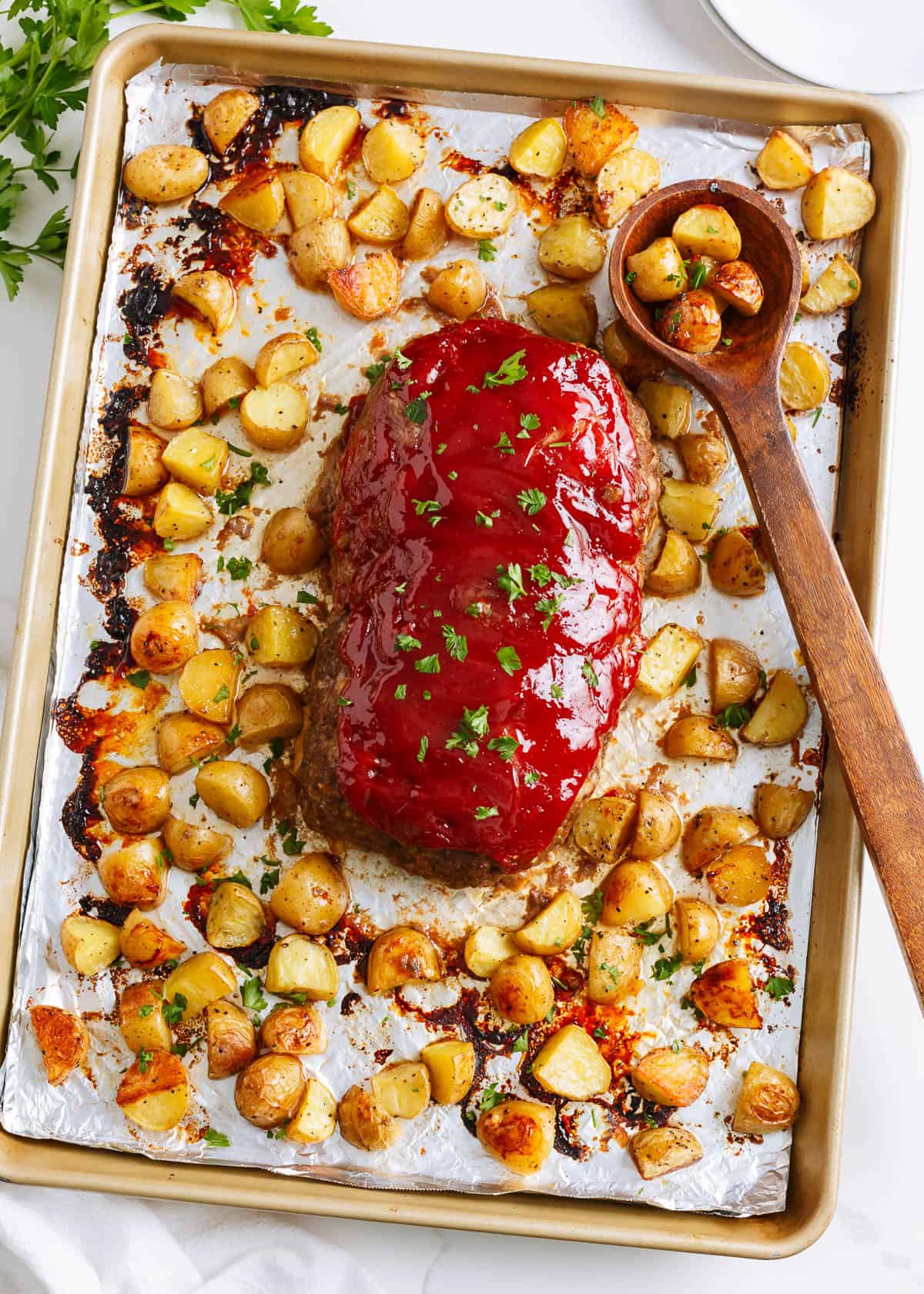 Sheet pan meatloaf with potatoes on a rimmed sheet pan.