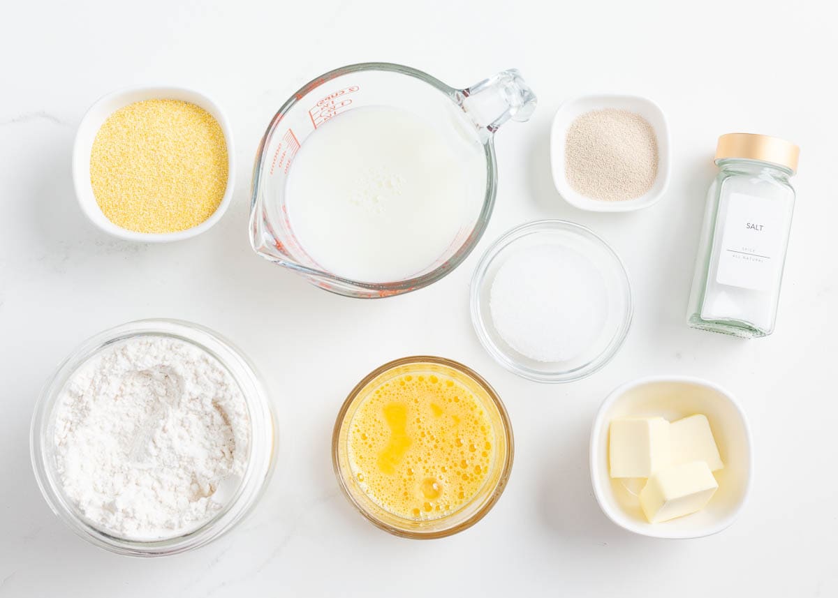 Milk, yeast, sugar, flour, salt, butter, whisked egg and cornmeal ingredients for English muffins.