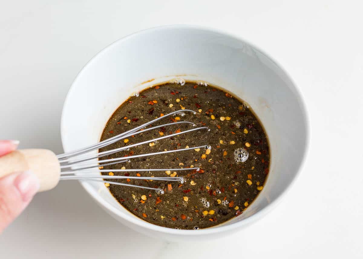 Whisking sauce in a bowl for ground beef and broccoli.