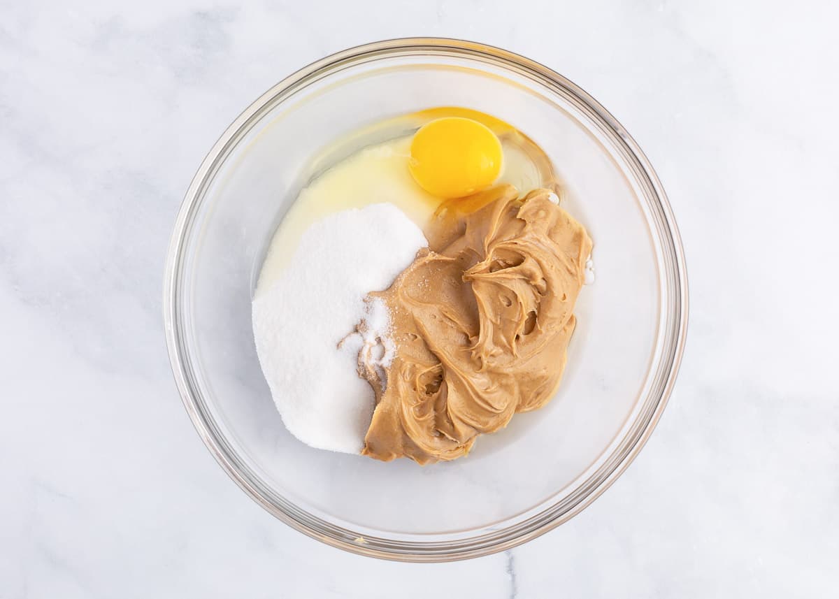 Egg, peanut butter and sugar in a bowl.