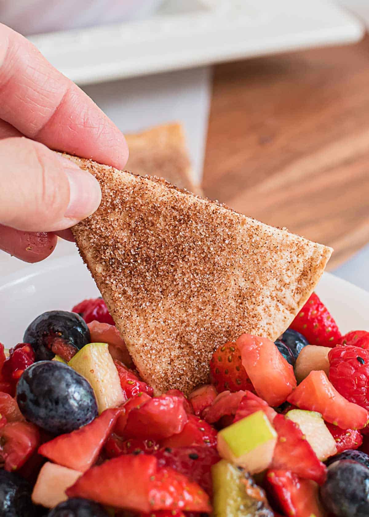 Dipping cinnamon tortilla chip in fruit salsa.