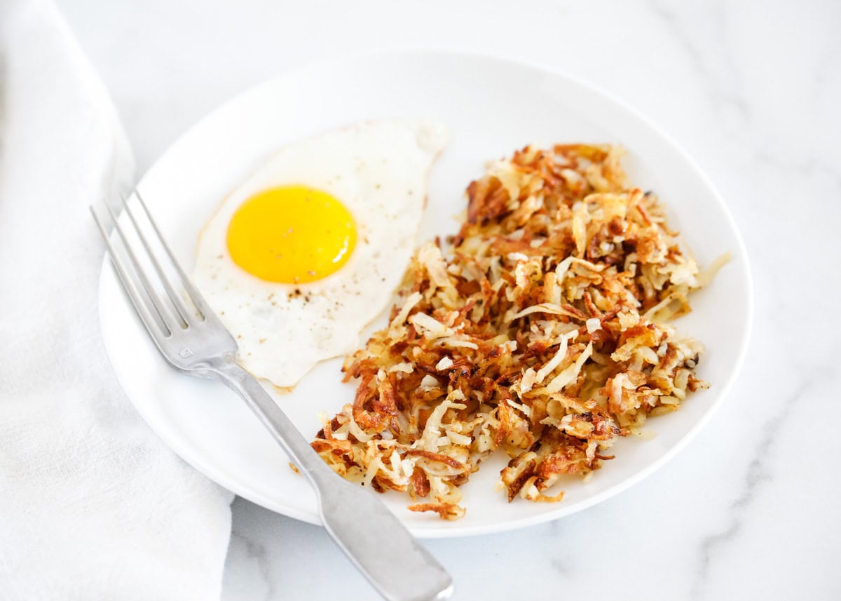 Homemade hash brown recipe on a plate with a cooked egg.