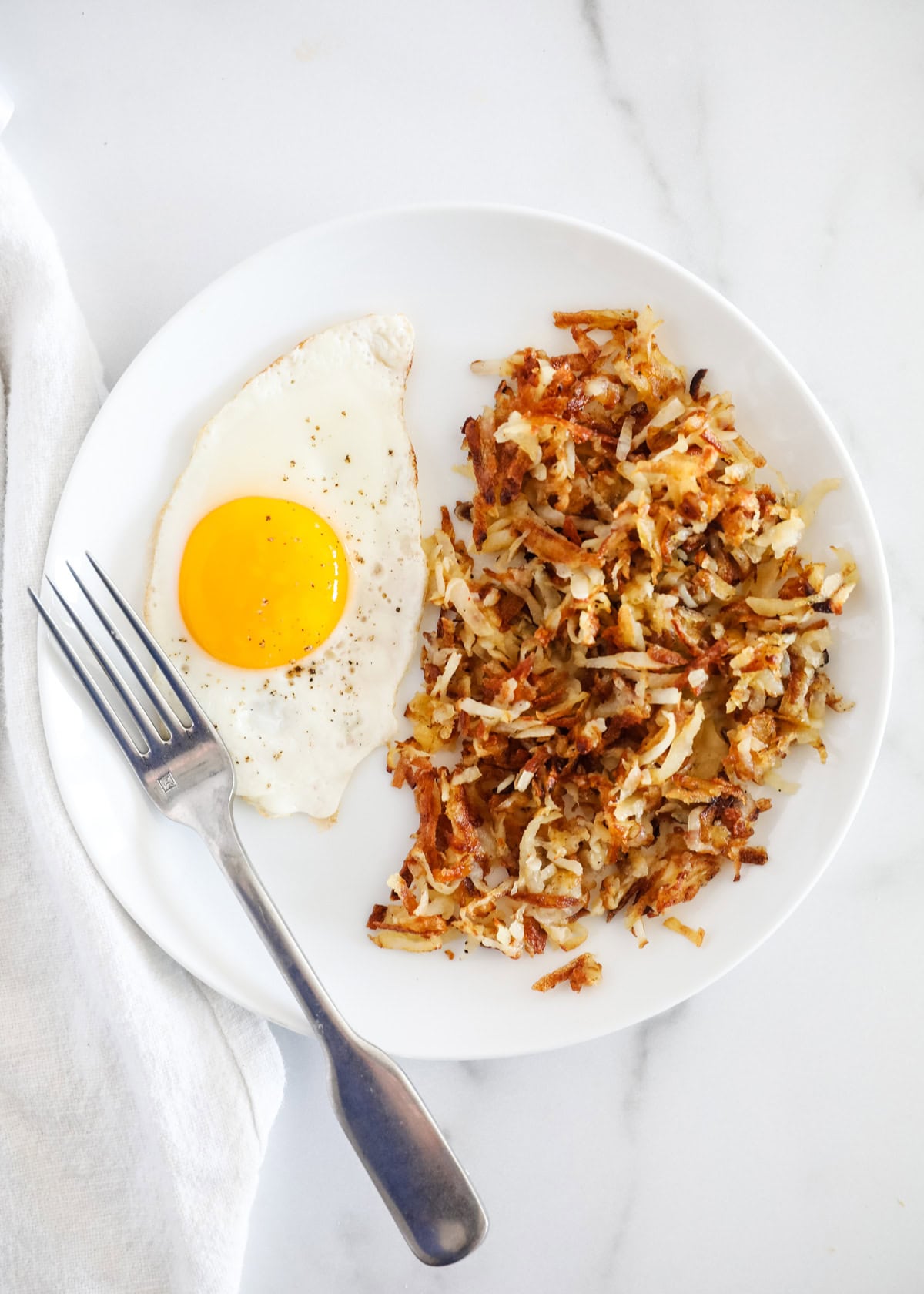 Homemade hash browns on a plate with an egg.