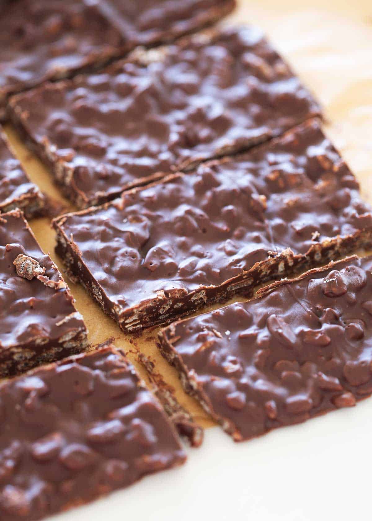 Homemade crunch bars cut into pieces on parchment paper. 