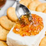 Pouring jalepeno jelly over cream cheese and crackers.