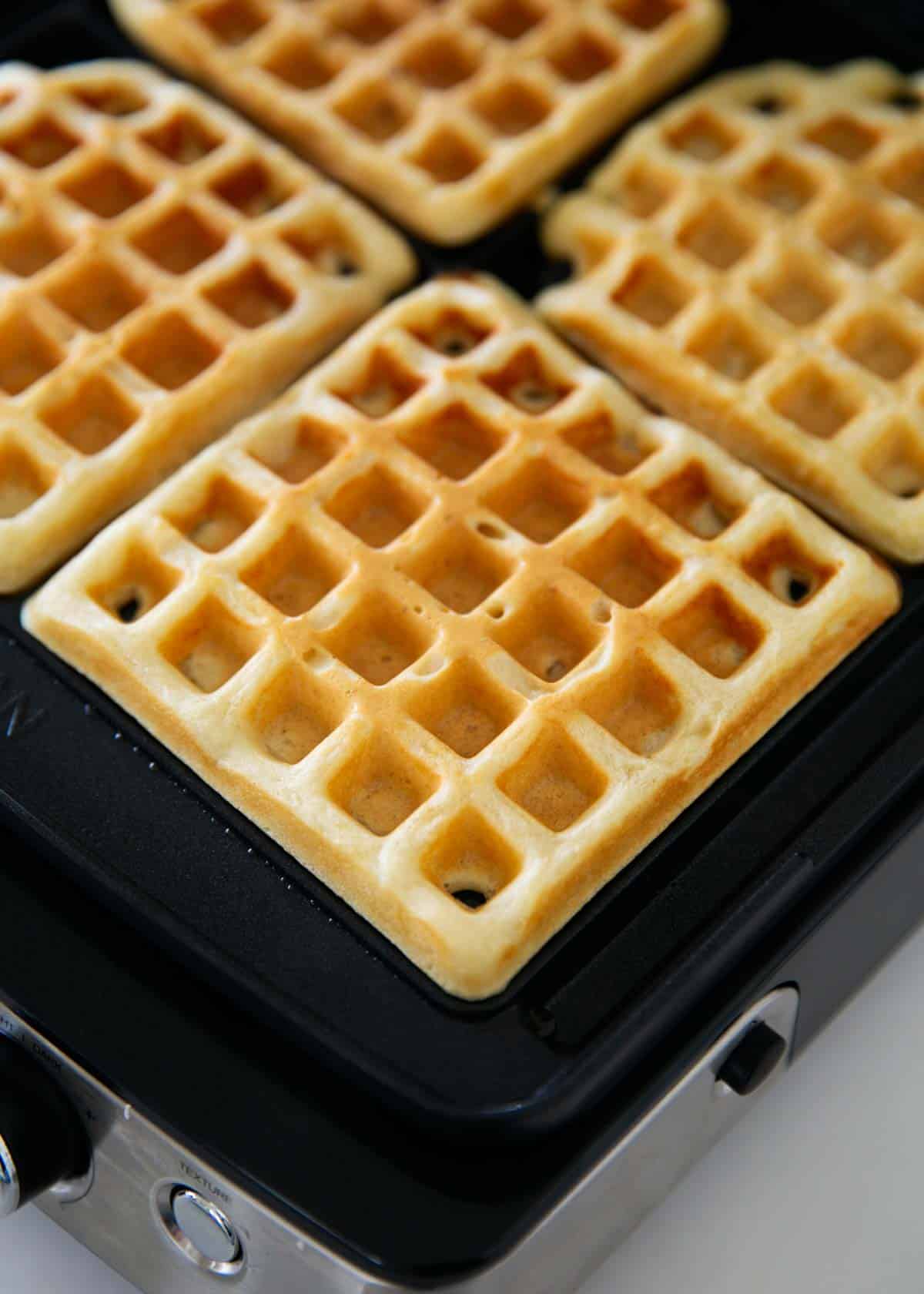 Cooked waffles on a waffle iron.