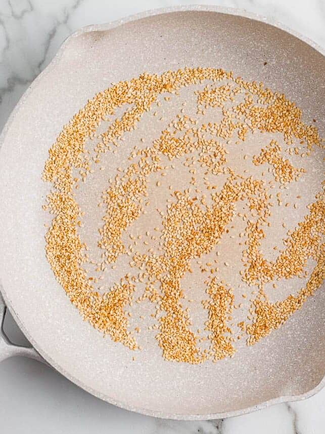 Toasting sesame seeds in a pan.