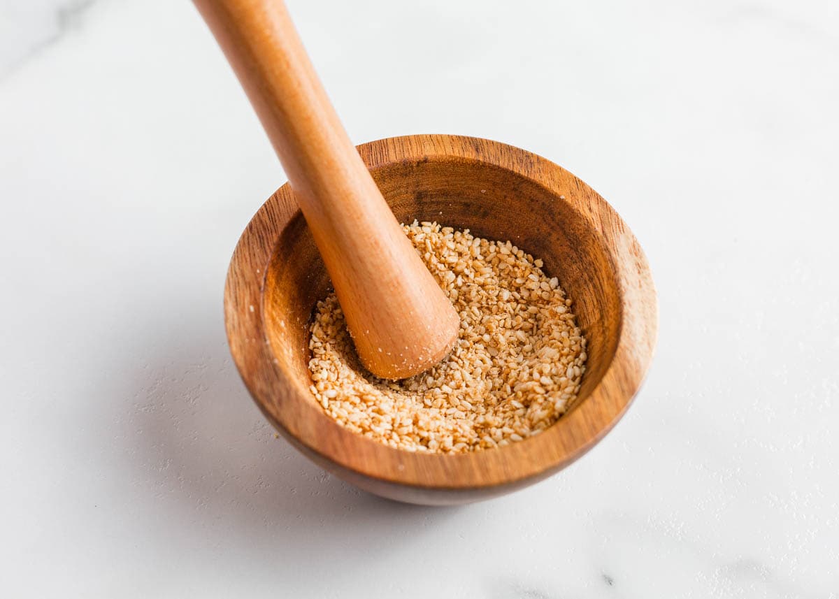 Crushing sesame seeds in a bowl.