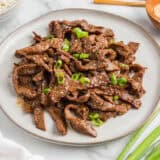 Beef bulgogi on a plate with green onions.