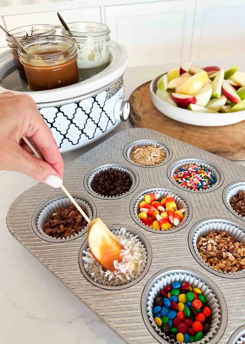 Dipping caramel apples into toppings.