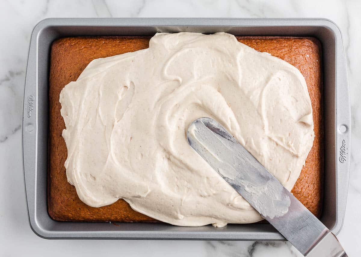 Spreading frosting onto pumpkin cake.