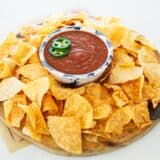 Tortilla chips and salsa on a board.