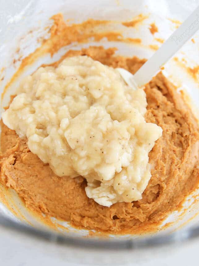 Pumpkin quick bread batter with mashed bananas being stirred in.