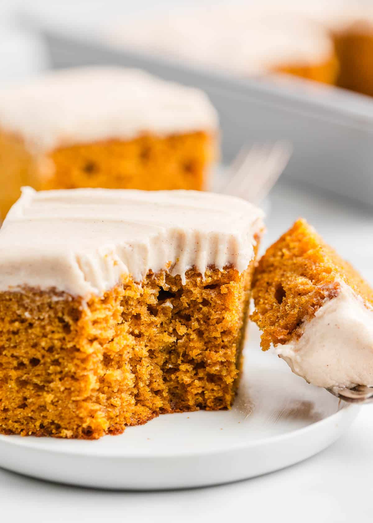 Pumpkin cake with a bite taken on white plate.