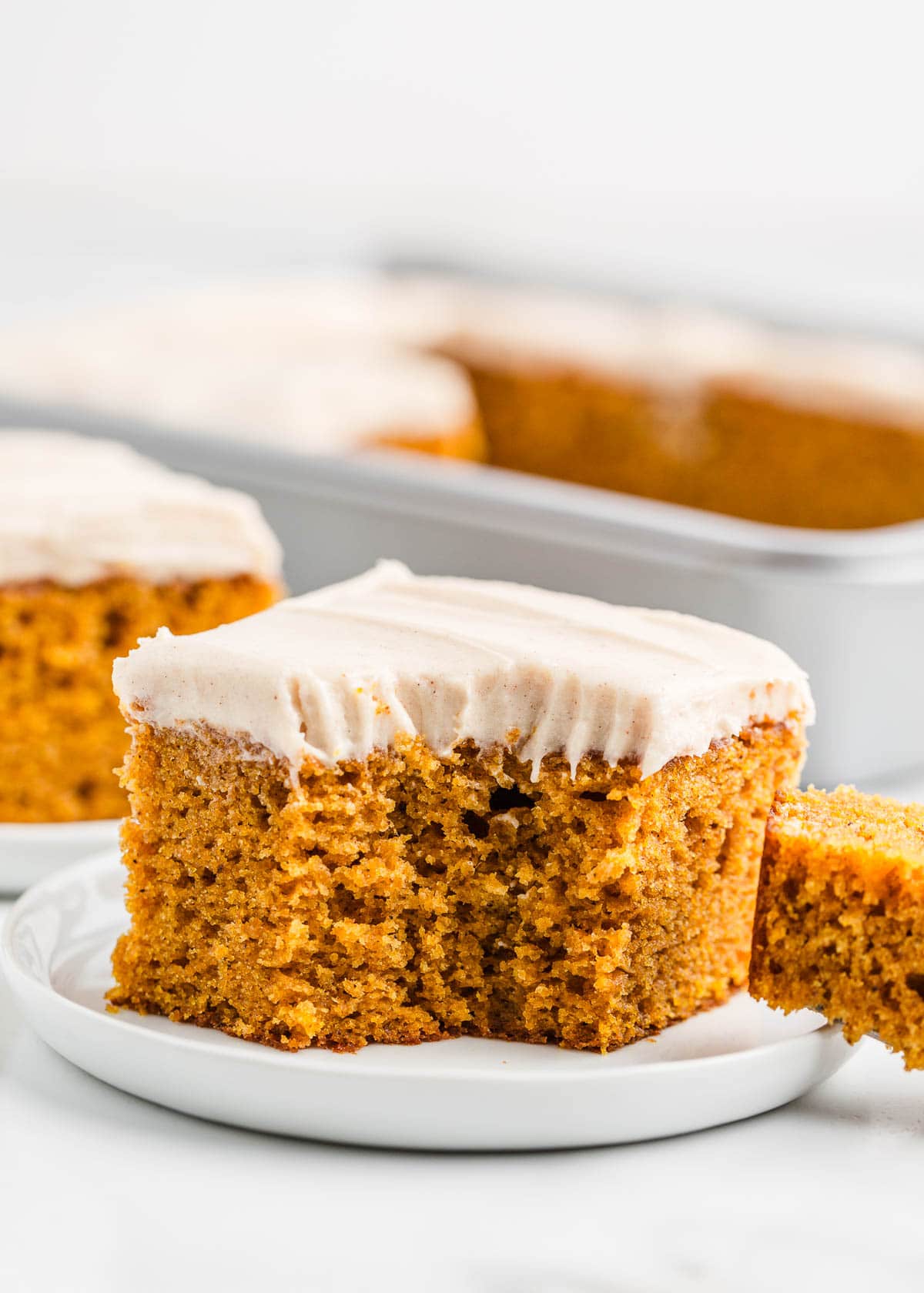 Slice of pumpkin cake with frosting on plate.