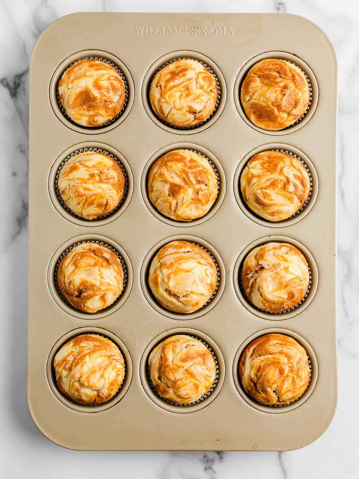 Pumpkin cream cheese muffins in a baking sheet.